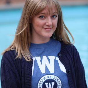 Breezy sitting in front of Red Square fountain wearing a blue WWU t-shirt under a dark blue sweater.