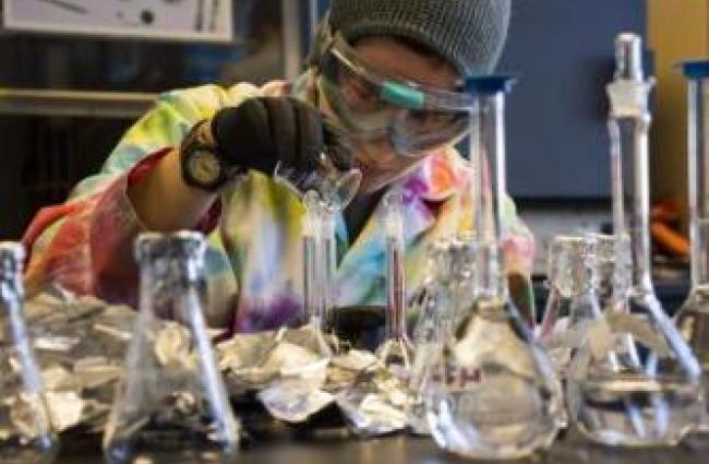Person wearing goggles working with test tubes in lab